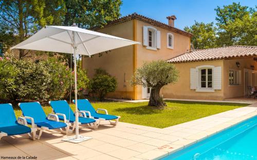 a group of chairs and an umbrella next to a pool at Lagrange Vacances Domaine de Fayence in Fayence