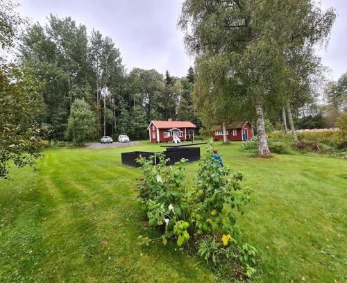 a red house in the middle of a green field at Fully equipped beautiful cottage in Nora