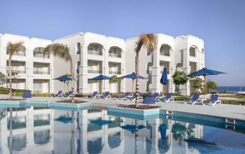 Cleopatra Luxury Resort Sidi Heneish - North Coast في مرسى مطروح: منتجع فيه مسبح وبه كراسي ومظلات
