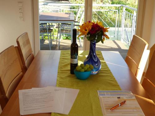 a table with a bottle of wine and a vase of flowers at Schauenburgblick in Oberkirch