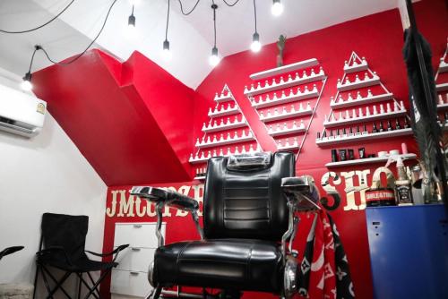 a barber chair in front of a red wall at Sunshine Guest House in Hua Hin