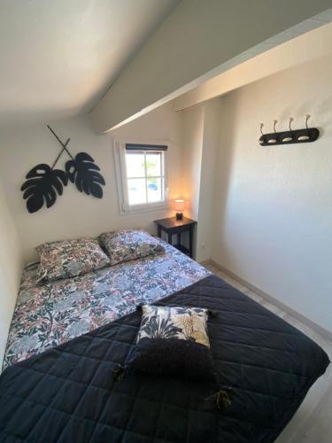 una camera da letto con un letto con un piumone blu e una finestra di Appartement Duplex Climatisé Le Trident a Saintes-Maries-de-la-Mer