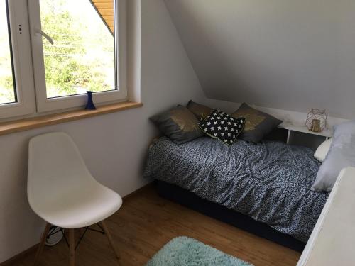 um pequeno quarto com uma cama e uma cadeira branca em Domek na wsi Roztocze Bania Bilard 