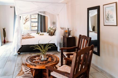 um quarto com uma cama, uma mesa e cadeiras em Gabus Safari Lodge em Otavi