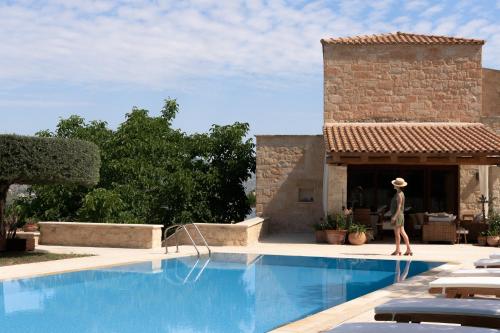 a woman walking next to a swimming pool at Malvazia Grand Estate, 4acre Immersed in Greenery, By ThinkVilla in Kermoútsi