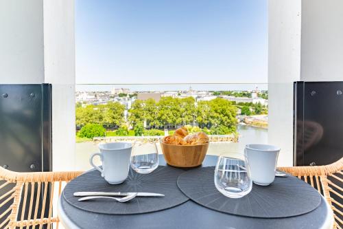 une table avec une corbeille de pain et des verres sur un balcon dans l'établissement Loire Enchantée - Appt sur l'île de Nantes, à Nantes