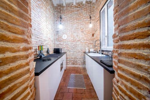 una cucina con muro di mattoni, lavandino e bancone di Le Montalbanais a Montauban