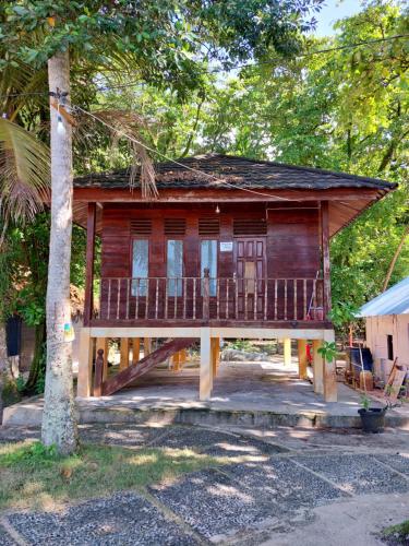a wooden house with a porch and a tree at Angso Duo Resort in Pariaman