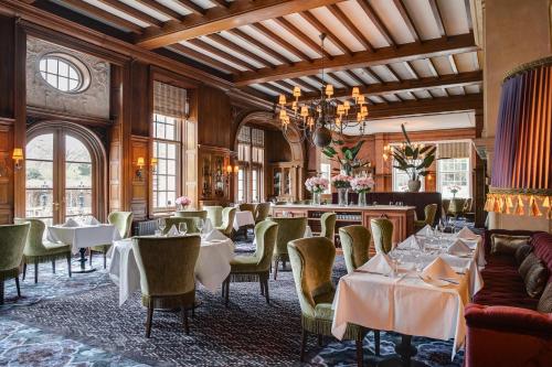 een restaurant met tafels en stoelen en een kroonluchter bij Landgoed Duin & Kruidberg in Santpoort-Noord