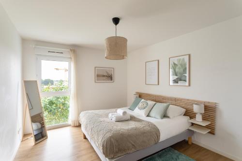 une chambre blanche avec un lit et une fenêtre dans l'établissement Le Mint - Appt 2 chambres avec parking, à Rennes