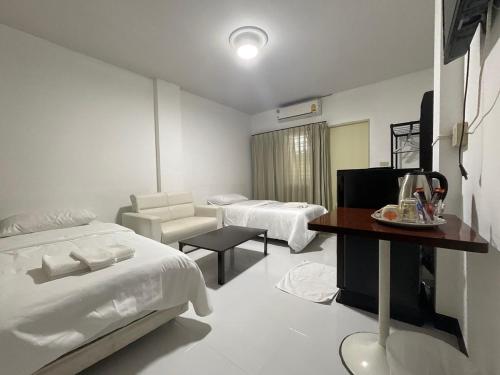 1 dormitorio con 2 camas, mesa y silla en Morning Home บ้านหมอนอิง, en Lopburi