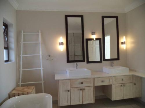 uma casa de banho com dois lavatórios e dois espelhos em NorthShore Beach House em Southbroom