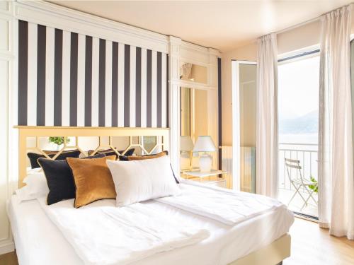 een slaapkamer met een groot wit bed en een groot raam bij La Caletta Hotel Bolognese in Brenzone sul Garda