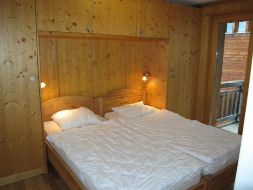 1 dormitorio con 1 cama grande y pared de madera en Residenz Plein Ciel, Wohnung CAPRICORNE VEYS240 en Veysonnaz