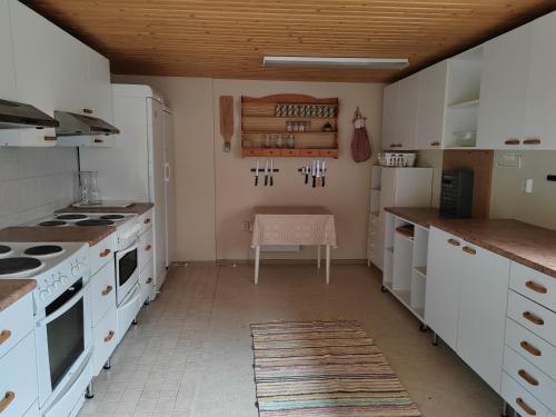 une cuisine avec comptoirs blancs et appareils électroménagers blancs dans l'établissement Puumaja maaseudulla, à Tuorila