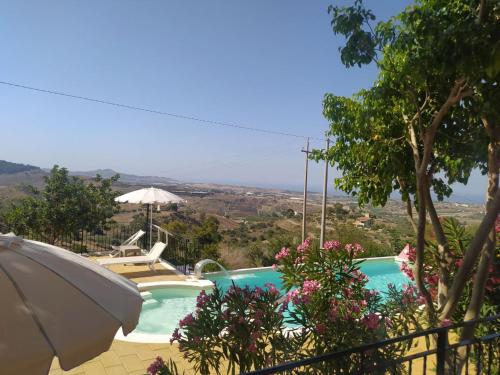 a swimming pool with an umbrella and a view at B&B Vento di Scirocco in Favara