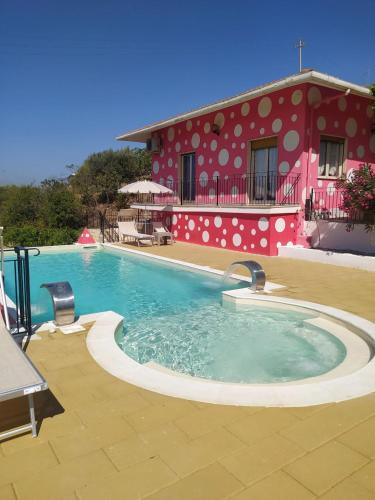 a swimming pool in front of a red building at B&B Vento di Scirocco in Favara