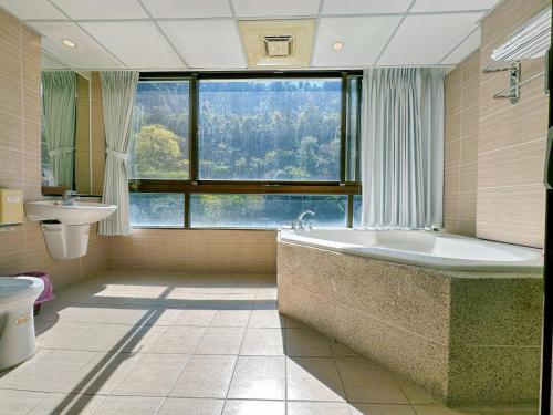和平的住宿－明治溫泉飯店B館東關溫泉飯店，一间带大窗户和浴缸的浴室