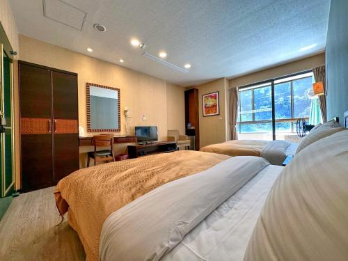 a bedroom with two beds and a desk and a television at Ming Zhi Hot Spring Hotel Building B Dongguan Hot Spring Hotel in Heping