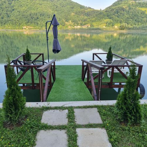 a picnic table with an umbrella in front of a lake at Unique Lake House Paradiso in Zvornik