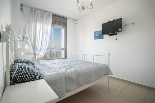 a white bedroom with a bed and a tv at Luxury Apartments Blue Wave in Ashdod