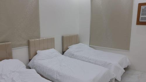 two beds with white sheets in a room at ابو عامر للشقق المفروشه in Al ‘Awālī