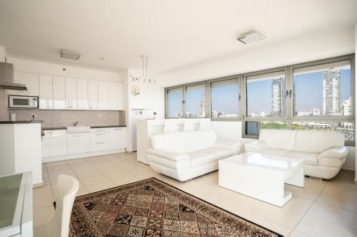 una sala de estar con muebles blancos y ventanas grandes. en Luxury Apartments Blue Wave en Ashdod