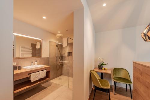 La salle de bains est pourvue d'un lavabo et d'un bureau avec deux chaises. dans l'établissement Rebenheim, à Termeno