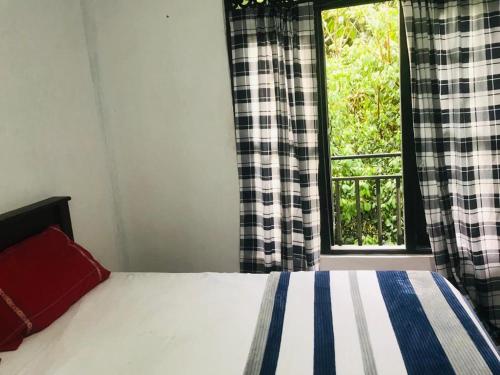 a bedroom with a bed in front of a window at River Side Guest house in Maskeliya