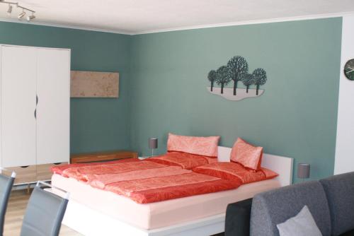 a bedroom with a bed with red sheets and trees on the wall at Ferienwohnung Jatta in Sankt Aldegund