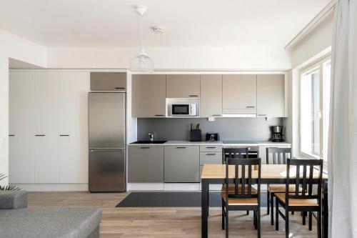 a kitchen with white cabinets and a table and chairs at Kotimaailma Apartments Loimu III in Oulu