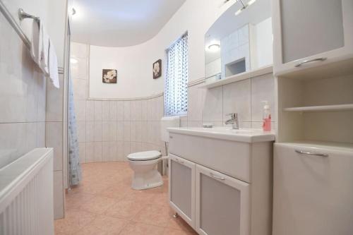 a white bathroom with a toilet and a sink at Villa B&M in Petrcane