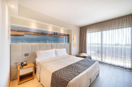 a hotel room with a bed and a large window at Laguna Park Hotel 4Superior in Bibione