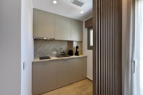 a kitchen with white cabinets and a sink at Anais Milos Suites in Adamas