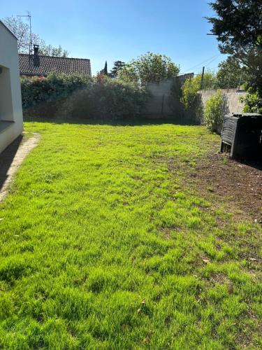 a yard with a green lawn with a fence at logement entier: suite chez Vanessa in Décines-Charpieu