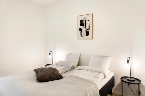 a bed with white sheets and a pillow on it at Kotimaailma Apartments Loimu II with Private Sauna in Oulu