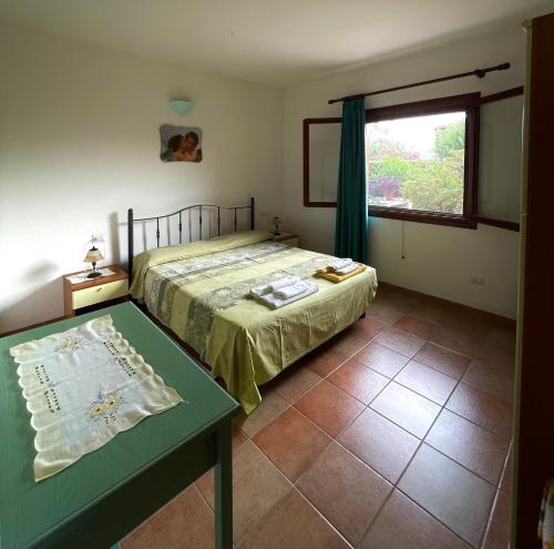 a bedroom with a bed and a table and a window at Casa Debili in San Teodoro