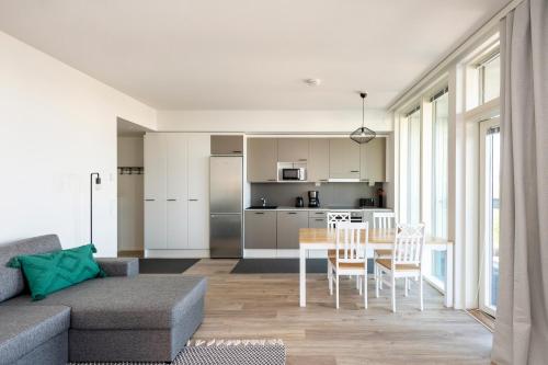 a living room with a table and a kitchen at Kotimaailma Apartments Loimu I in Oulu