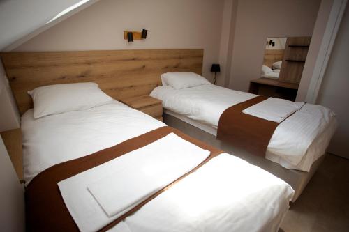 two beds in a hotel room with white and brown sheets at Soul River e cucina in Pančevo