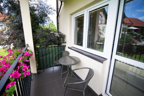 d'une petite table et de chaises sur un balcon fleuri dans l'établissement Piaskowy Dom, à Jantar