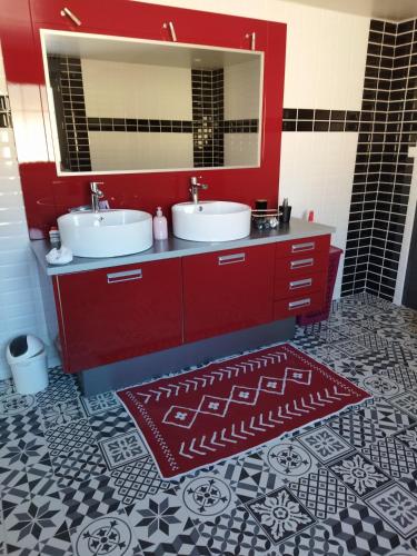 - une salle de bains rouge avec deux lavabos et un miroir dans l'établissement Chez Monique, à Maubert-Fontaine