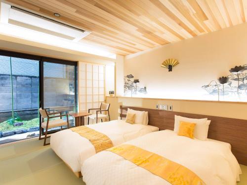 two beds in a room with a table and chairs at 枳殻の杜 Kikoku no mori in Kyoto