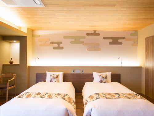 two beds in a room with a wall with japanicans at 枳殻の杜 Kikoku no mori in Kyoto