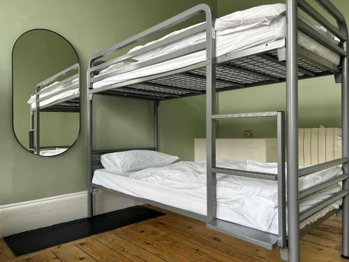 a bedroom with two bunk beds and a mirror at Cricketers Hostel in London