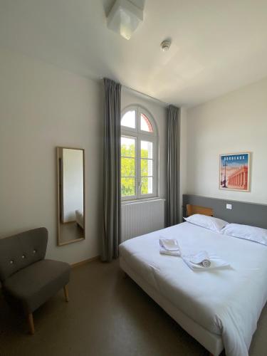a bedroom with a bed and a chair and a mirror at Hotel Saint Louis Beaulieu - Bordeaux in Bordeaux