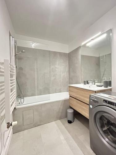 une salle de bain avec baignoire et machine à laver dans l'établissement Sublime flat - Heart of Paris - Le Marais, à Paris