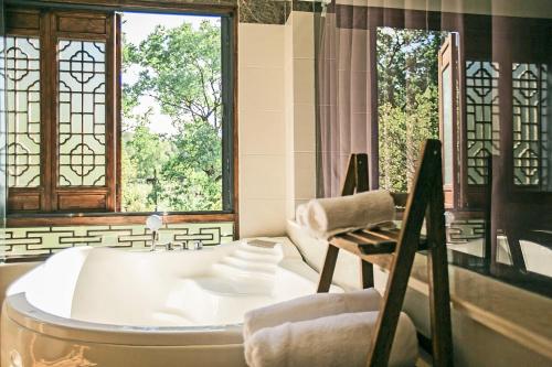 a bathroom with a tub and a large window at Alina Garden Boutique Resort Huangshan Hongcun in Huangshan Scenic Area
