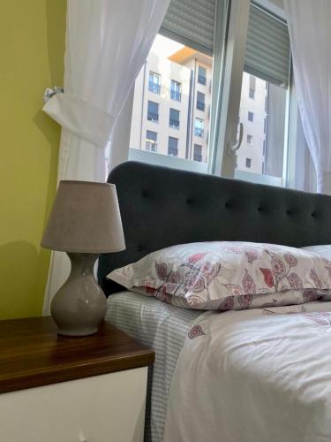 um quarto com uma cama, uma janela e um candeeiro em Prishtina Rent Apartment B Street em Pristina