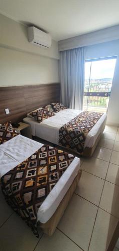 three beds in a room with a window at Barretos Thermas Resort in Barretos