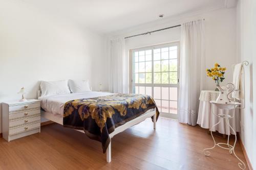 a white bedroom with a bed and a window at ALTIDO Superb house with garden and patio in Charneca